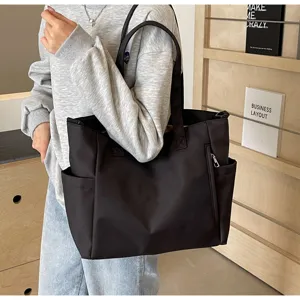 Black nylon tote bag detail showcasing large capacity, dual handles, and side zipper pocket.