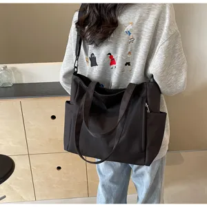 Detailed view of the black waterproof nylon tote bag showing strap and side pocket design.
