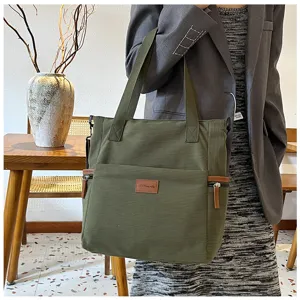 Large capacity green corduroy tote bag detail showing shoulder strap, front pocket and badge.