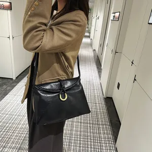 Minimalist black soft leather shoulder bag for women with elegant braided ring clasp design.