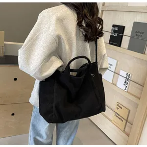 Detailed shot of black corduroy tote bag with dual handles in stylish lifestyle setting.