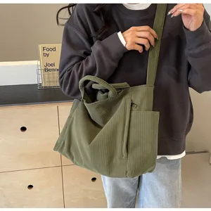 Detail view of the large capacity green corduroy tote bag showing front zipper pocket.