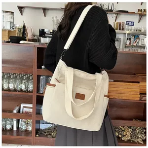 Detail shot of the large corduroy tote bag in beige, showing side pocket and shoulder strap.