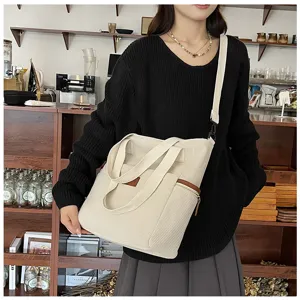 Beige corduroy tote bag detail shot, showing textured fabric, shoulder strap and sturdy handles.