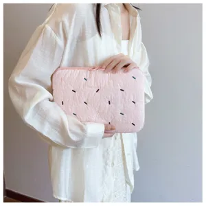 Close-up detail shot of the pink quilted embroidered laptop sleeve showing fine fabric texture.