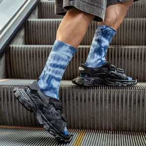 Calze al polpocchio tie-dye da uomo abbinate a sandali neri spessi ed eleganti per lo streetwear.