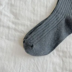 Gros plan détaillé de chaussettes en tricot côtelé gris foncé avec une texture douce.