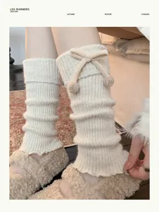 Close-up detail of knitted leg warmers with cute bow and pom-poms for winter warmth style.