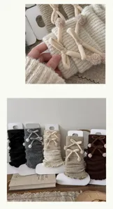 Close-up detail of knitted leg warmers with velvet bows and fluffy pom-pom accents.