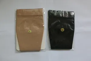 Vista detallada de mangas de compresión para pantorrillas beige y negras en bolsas de plástico.