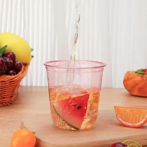 Gros plan d'un gobelet en plastique rose de 12oz avec de l'eau et des fruits pour fête.
