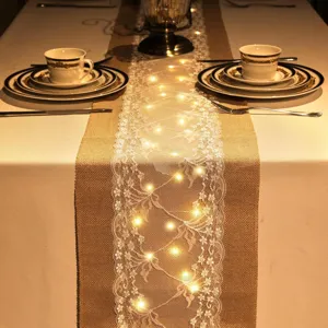 Jute tafelloper met witte kant en led-lampjes, rustieke tafeldecoratie voor feesten en bruiloften.