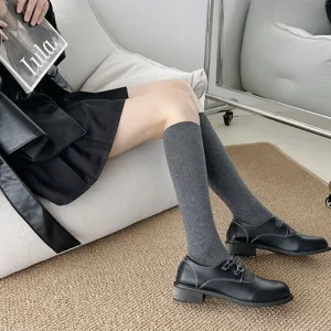 Chaussettes grises tendance pour femmes assorties de chaussures en cuir noir pour le style.