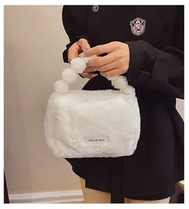 Detailed view of the cute white plush cosmetic handbag featuring fluffy pom pom handle design.