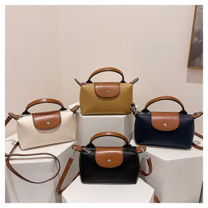Detail shot showing multiple leather dumpling bags in various colors on display pedestals.