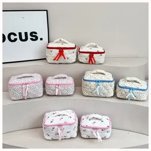 Quilted cosmetic bag detail showing floral and cherry prints with smooth zipper closure.