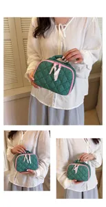 Detail view of green quilted cosmetic pouch with pink polka dots and cute ribbon zippers.