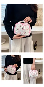 Quilted floral makeup bag detail with delicate pink trim, bow decoration and carry handle.