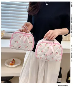 Quilted cosmetic bag with strawberry print and pink bow, portable makeup storage pouch.