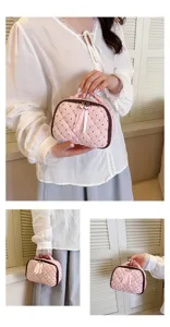 Pink quilted cosmetic bag detail view, cotton polka dot makeup pouch with cute ribbon pull.