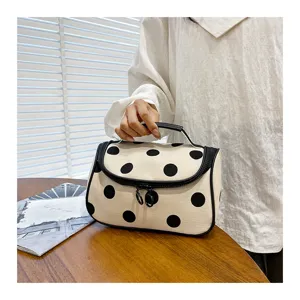 Close-up detail shot of the elegant polka dot cosmetic bag with zipper and handle.