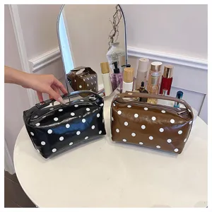 Detail view of stylish black and brown polka dot PU leather cosmetic storage bag with handle.