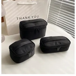Scène van zwarte cosmetische tasjes set, minimalistische stoffen reis make-up pouch detail.