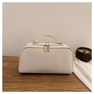 Nahaufnahme einer cremeweißen Kosmetiktasche mit Doppelreißverschluss auf Holztisch.