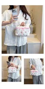Details of the quilted floral cotton cosmetic bag showing floral embroidery and pink zipper.