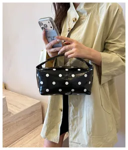 Black and white polka dot makeup bag detail showing glossy PU leather texture and strap.