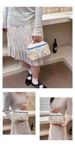 Quilted floral cosmetic bag detail view, showing soft cotton fabric, blue zipper and ribbon.