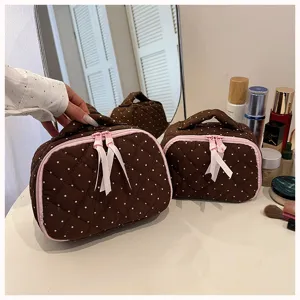 Detail view of the cute quilted polka dot cosmetic bag with pink ribbon and zipper pull.