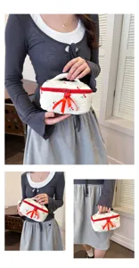Close-up detail shot of white quilted cosmetic bag with red cherry print and bow.