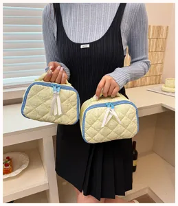 Detailed close-up of quilted polka dot cosmetic bag with cute ribbon zipper pulls and blue trim.