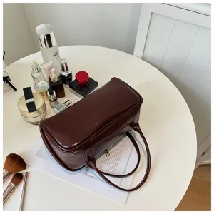 Dark brown leather cosmetic bag detailed view, elegant barrel handbag storage design.