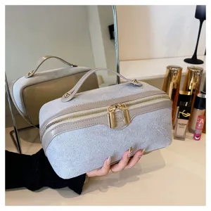 Detailed view of the soft suede cosmetic pillow bag with gold zipper and top handle.