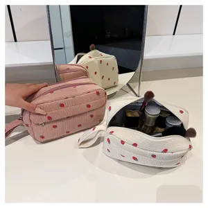 Close-up of portable corduroy cosmetic bag with cute strawberry pattern, ideal for daily makeup.