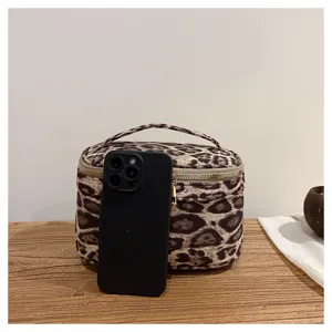 Detail shot showing the leopard print cosmetic bag texture and portable size with phone reference.