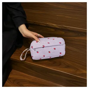 Close-up detail of the purple corduroy strawberry print cosmetic pouch with durable zipper.