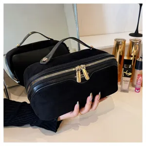 Close-up detail of black suede cosmetic bag showing smooth metal zipper and soft texture.
