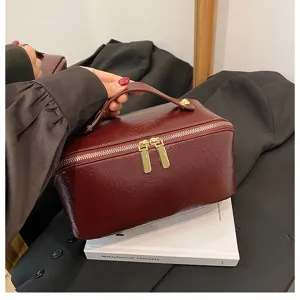 Burgundy PU leather cosmetic bag detail, large capacity vanity case with gold zippers and handle.