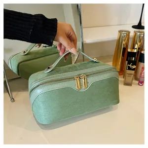 Green suede cosmetic bag with double zipper and top handle for travel and daily storage.