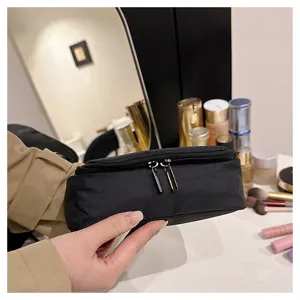 Black minimalist cosmetic bag detail, portable toiletry storage pouch with dual zippers.