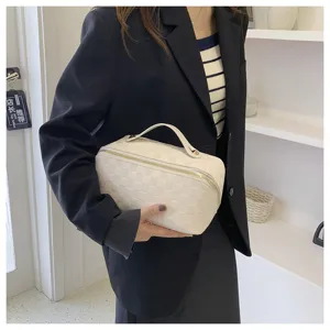 Detailed view of the elegant beige checkered cosmetic bag with gold zipper and top handle.