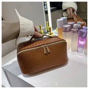 Vue détaillée d'une trousse de maquillage marron en cuir PU tressé sur un meuble.