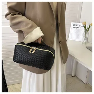 Vue détaillée du sac cosmétique en cuir PU tissé noir avec fermetures éclair dorées.