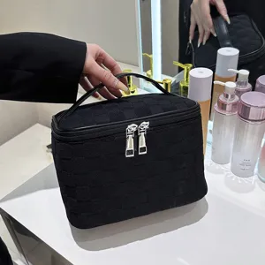 Black woven cosmetic bag with large capacity, portable handle and smooth zipper closure.