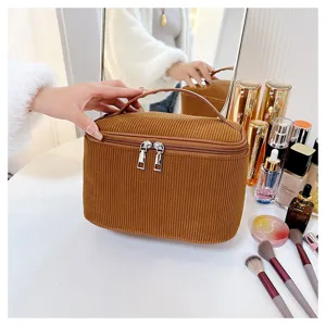 Corduroy cosmetic bag detail showing soft texture, smooth dual zippers and portable handle.