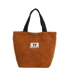 Bruine ribfluwelen tote bag met zwarte handvatten, klassiek vintage design voor dagelijks gebruik.