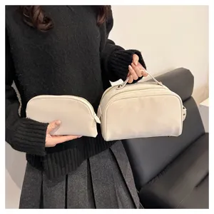Detail view of beige cosmetic bag set, showing zipper closure and portable handle design.